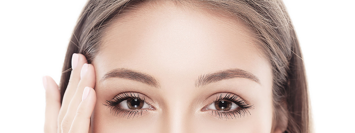 Forehead of a women with brown eyes and brown hair touching her temple with her right hand