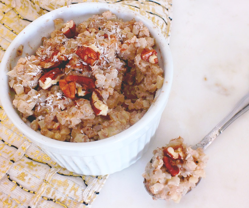 Bowl of Coconut Cauliflower "Rice" Pudding with a spoonful of pudding sitting next to the bowl