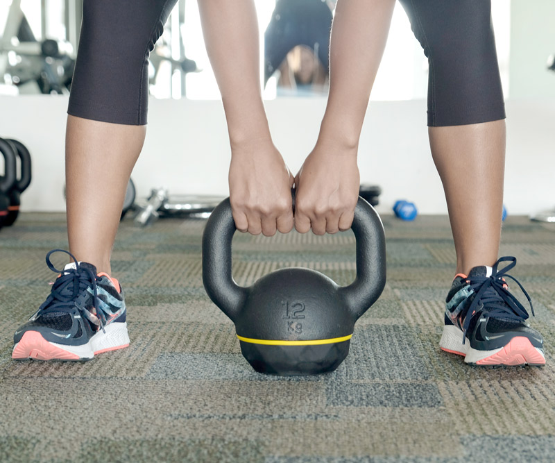 Athletic woman bending over to pick up a kettlebell