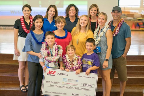 Kapono and Duke Pavao (front left and center) accept a $10,000 donation to Kapiolani made by Duracell in honor of the Pavao family. The presentation was part of a surprise ceremony held for the brothers at Wilcox Elementary Jan. 26, 2018.