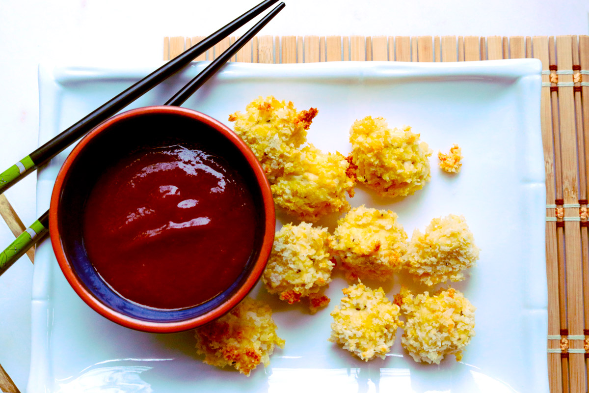 A pair of chopsticks rests on a serving dish with pieces of Tofu Katsu and a bowl of homemade Katsu Sauce