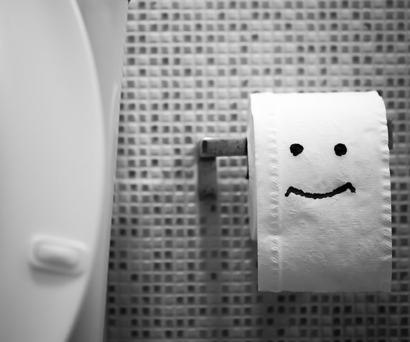 Close-up of a happy face drawn on a roll of toilet paper