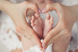 Baby feet in mother's heart shaped hands