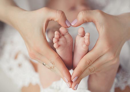 Baby feet in mother's heart shaped hands