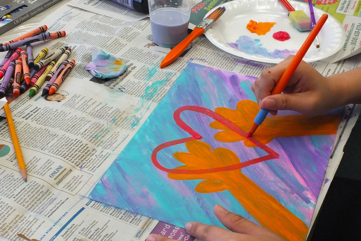 A cancer patient paints a heart on a colorful canvas.