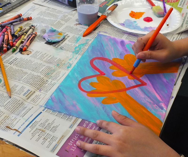 A cancer patient paints a heart on a colorful canvas.