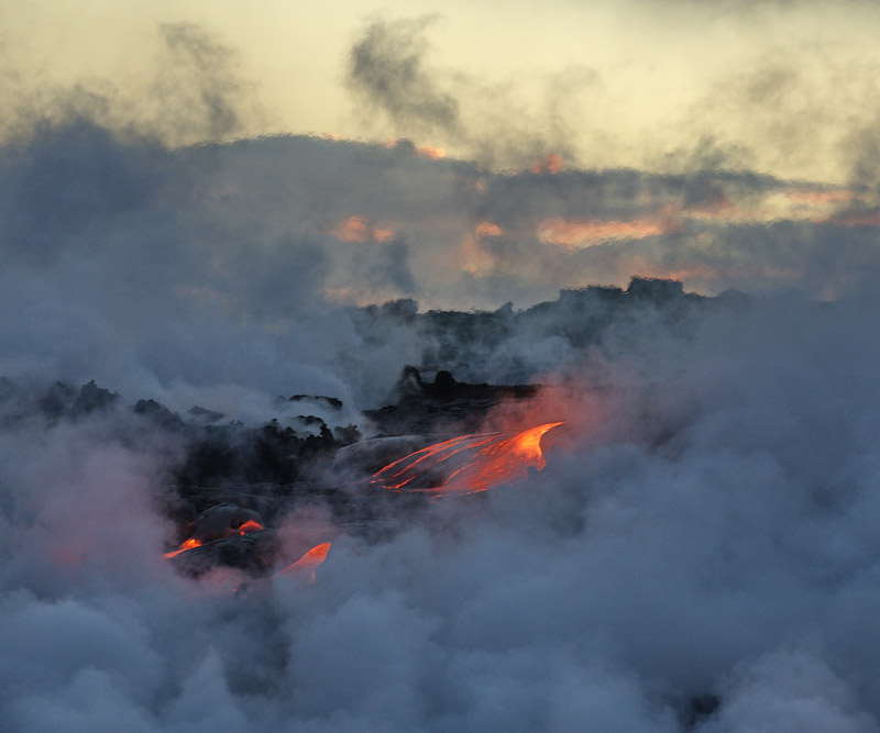 a thick layer of vog clouds the air around an active lava field
