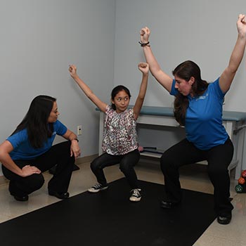 Physiotherapist and doctor exercising with young patient