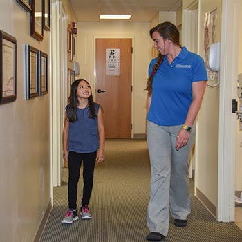 Physical therapist and young patient walking in the hallway of the Bone and Joint Center