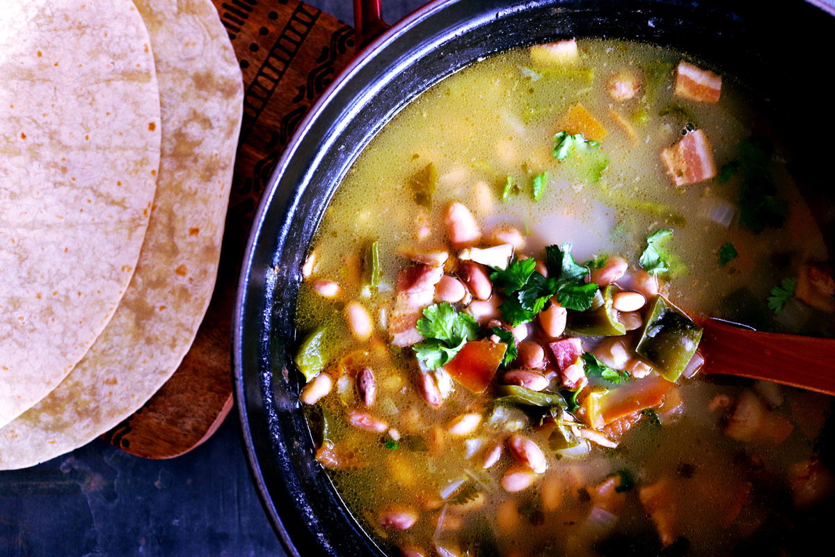 A pot of Slow-Simmered Pinto Beans with a side serving of tortillas