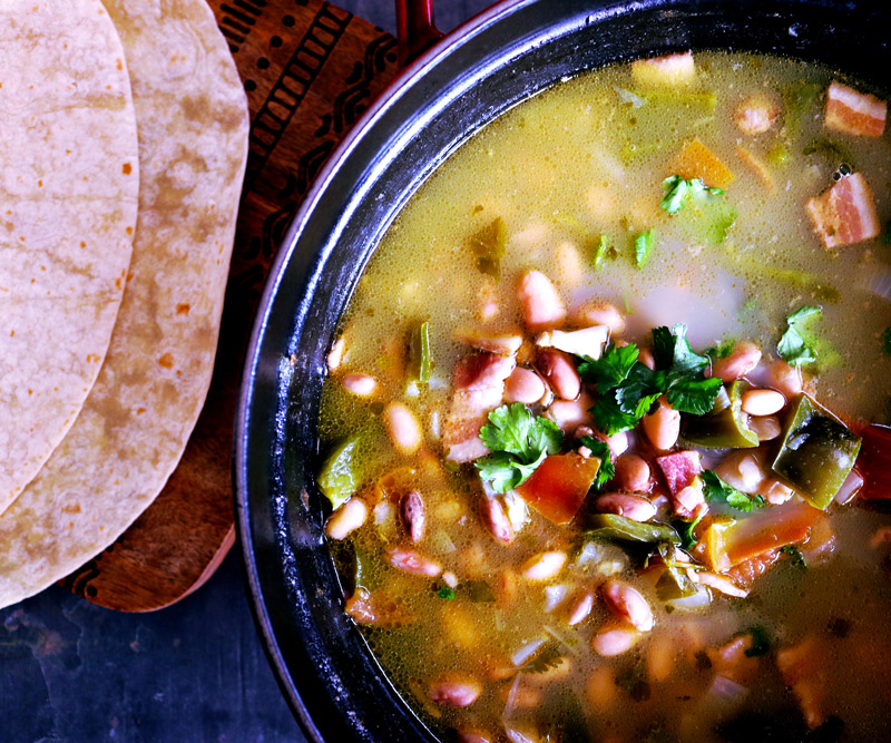 A pot of Slow-Simmered Pinto Beans with a side serving of tortillas