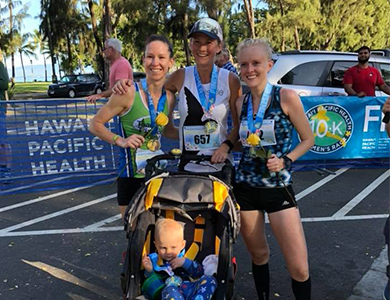 Three race participants of the women's 10 k standing behind stroller