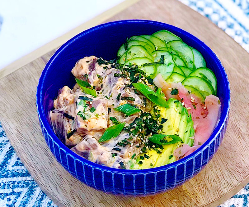 a Spicy Ahi Tuna Bowl sits on a decorative cutting board and mat