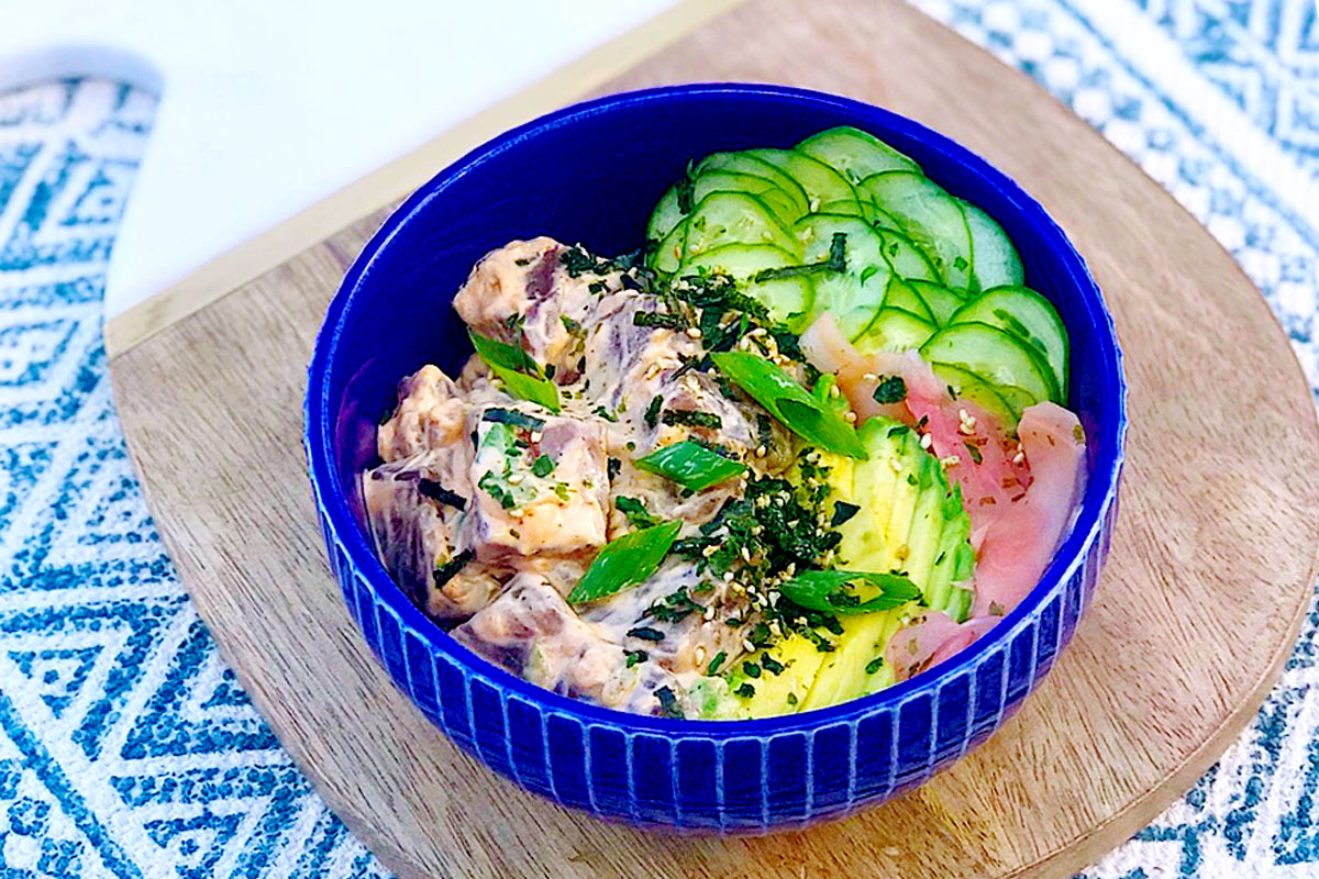 a Spicy Ahi Tuna Bowl sits on a decorative cutting board and mat