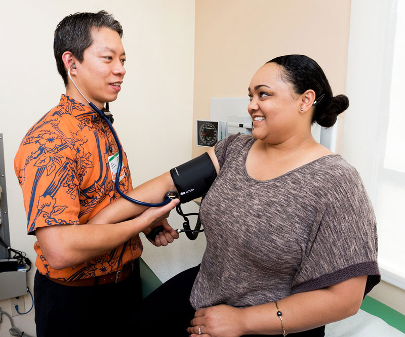 Dr. Jason Pirga reads a female patient's blood pressure in a clinic at Straub Medical Center