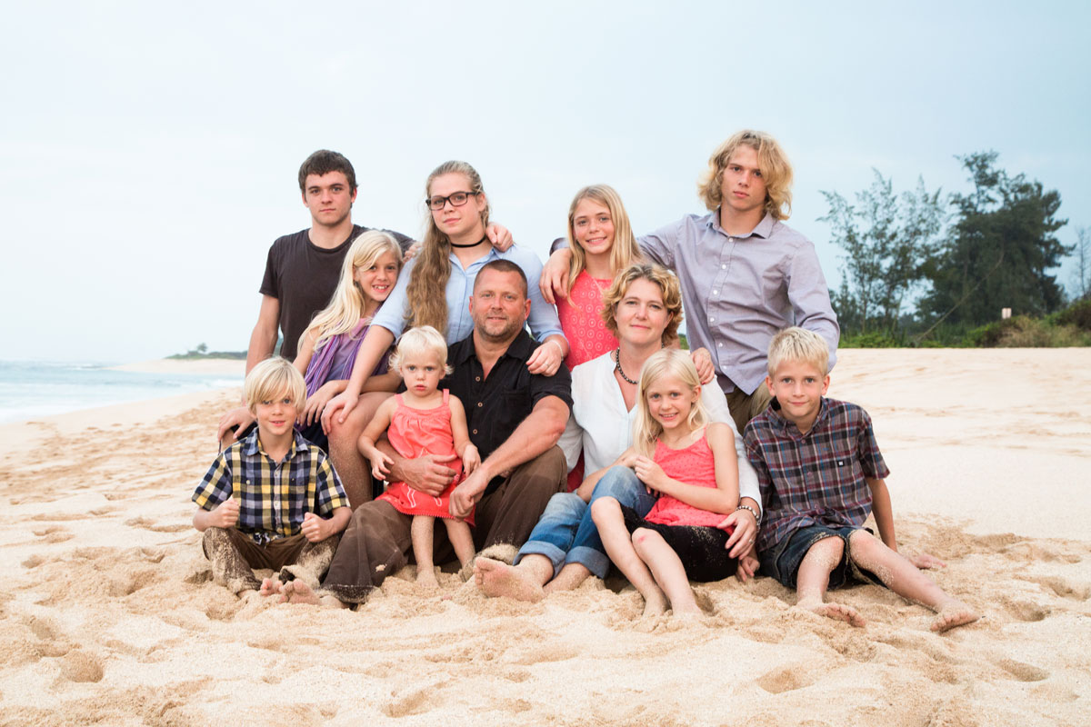 Casey Schmidt sits on a beach with her husband and nine children