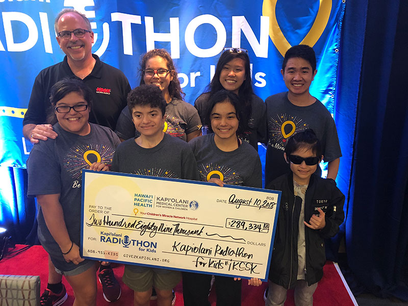 Group of 8 people holding large check donation