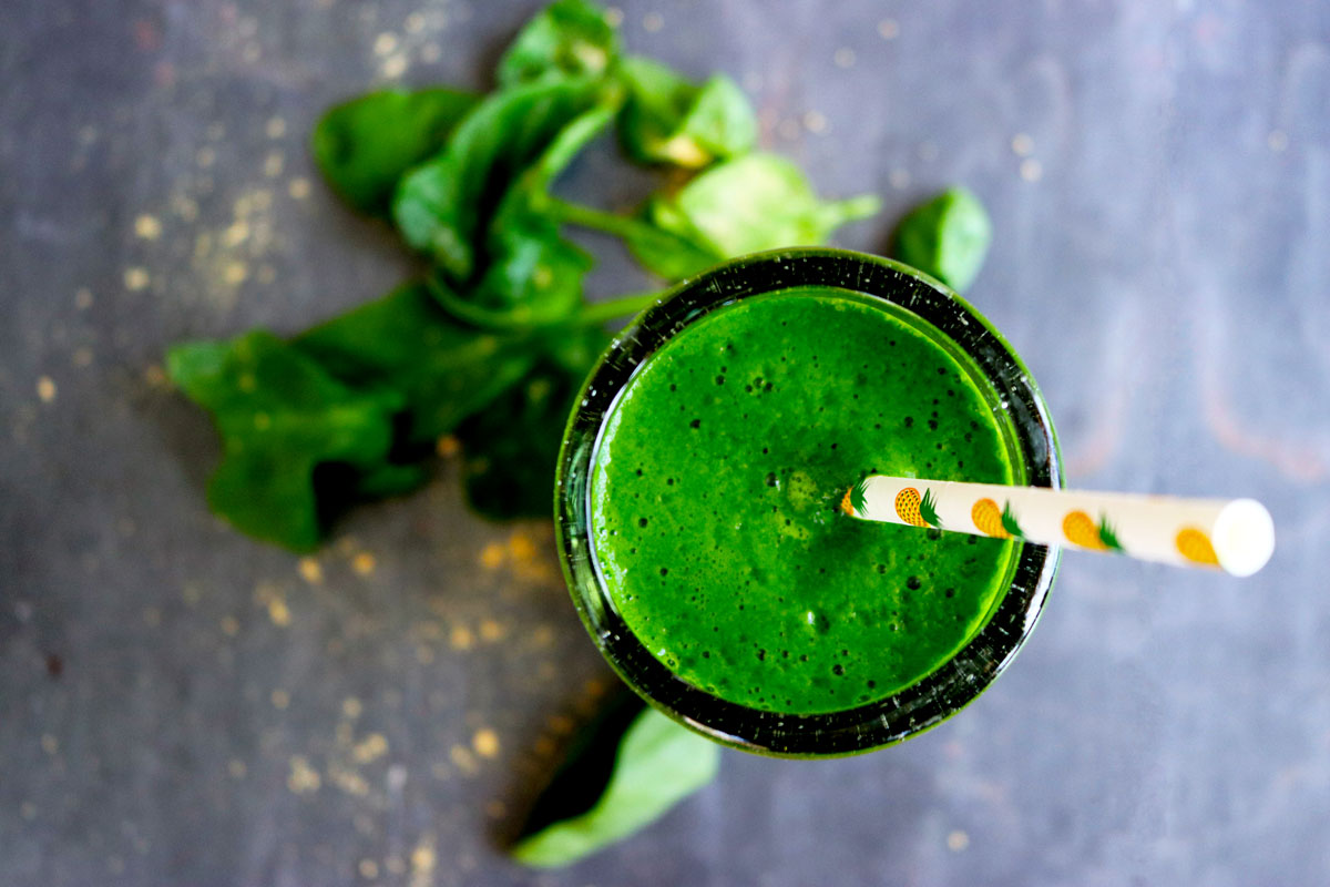 Green Ginger Smoothie in a tall glass with a paper straw