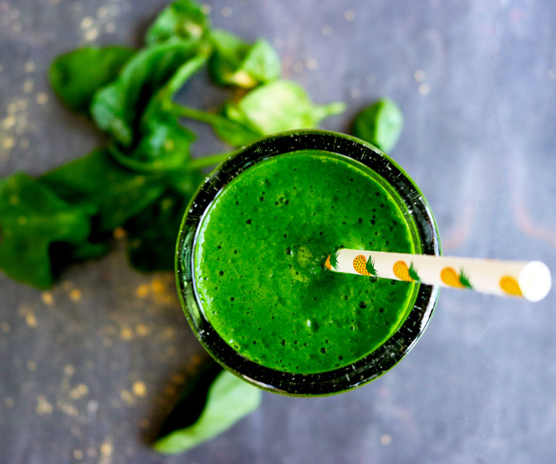 Green Ginger Smoothie in a tall glass with a paper straw