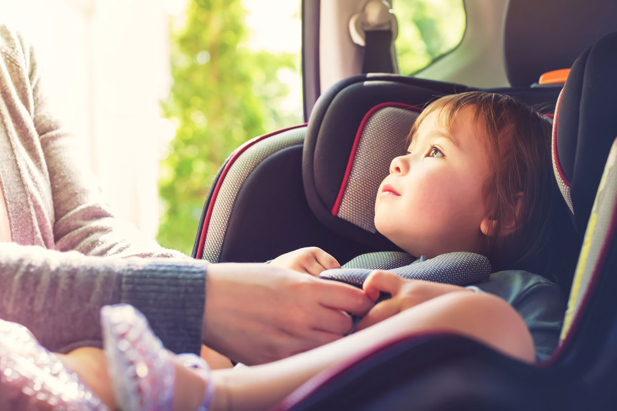 young child getting buckled into a car safety seat