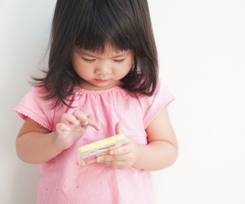 young toddler playing with games on a cell phone