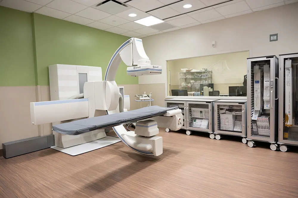 Interventional radiology suite with specialized equipment and supplies in a clinical environment.