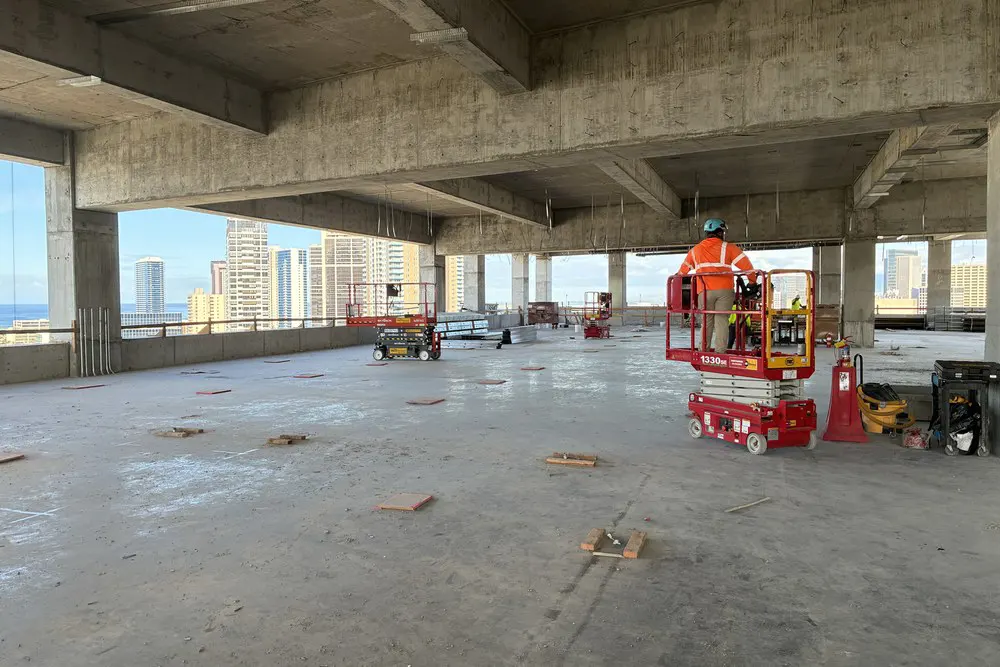 A worker operates a lift inside the open concrete floor on Level 20.
