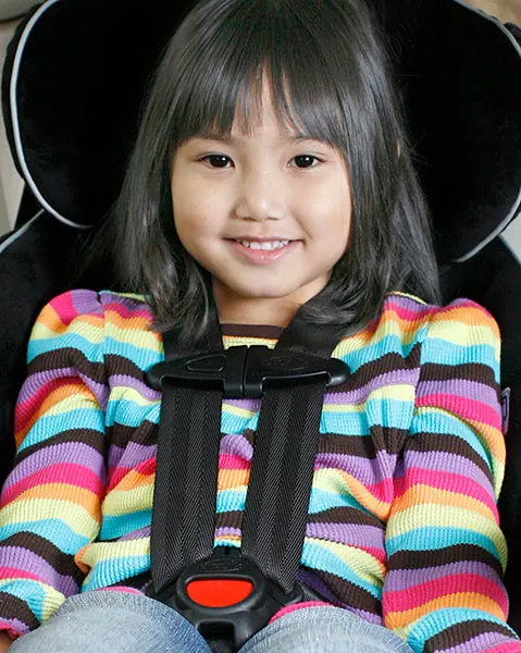 Smiling young girl in car seat.