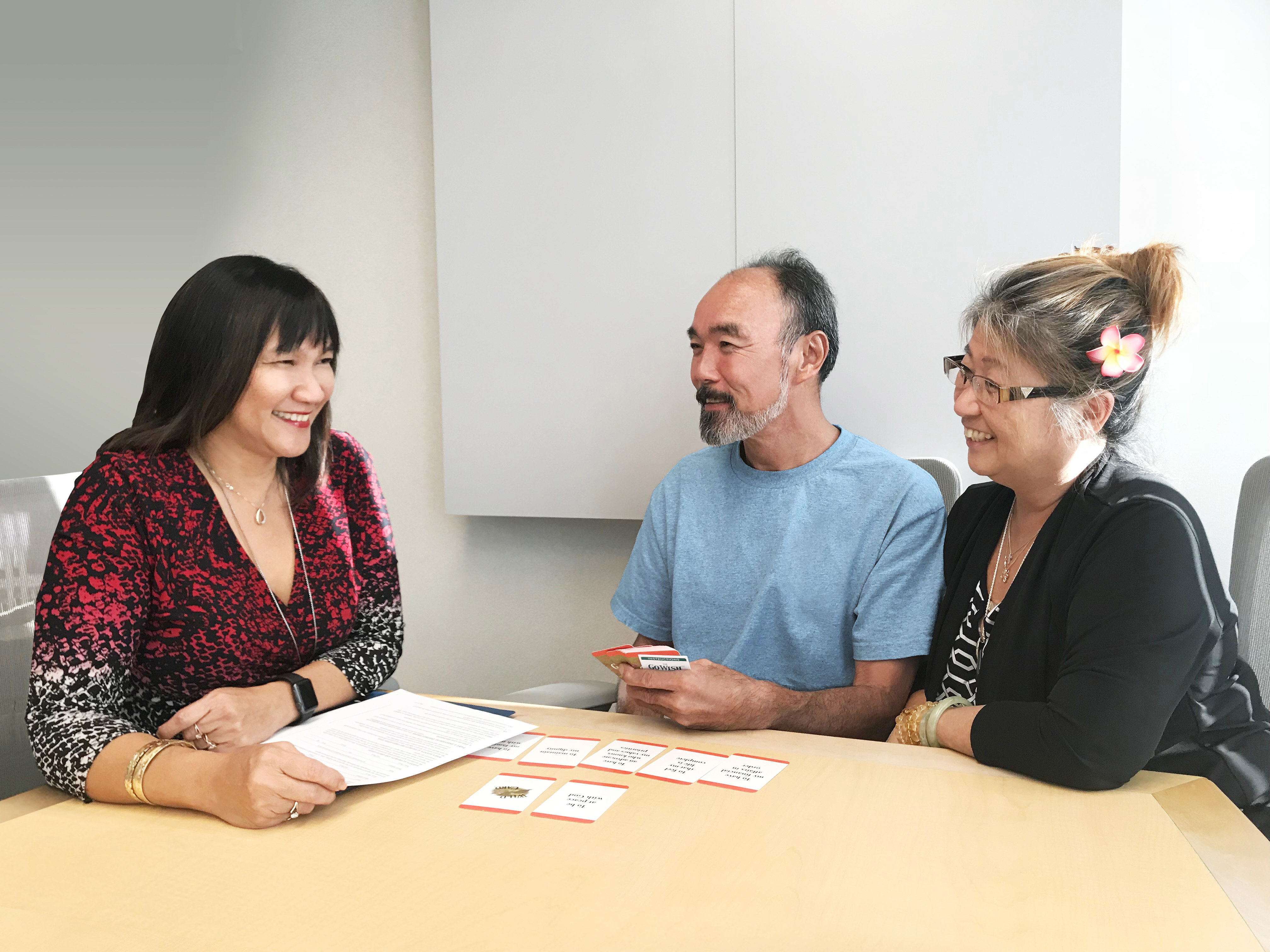 Smiling older couple meeting with an advance care planning facilitator at a table.