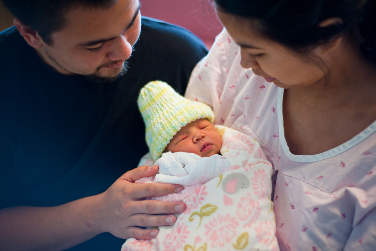 Two parents holding their newborn baby.