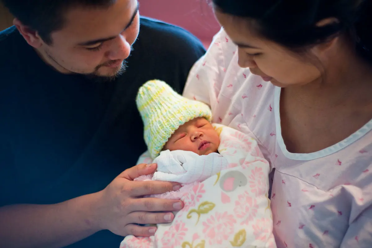 Two parents holding their newborn baby.