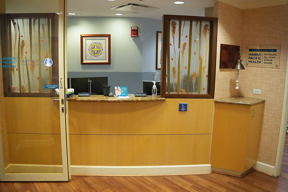 Reception desk in medical office of a women's cancer center with signage and a bell.