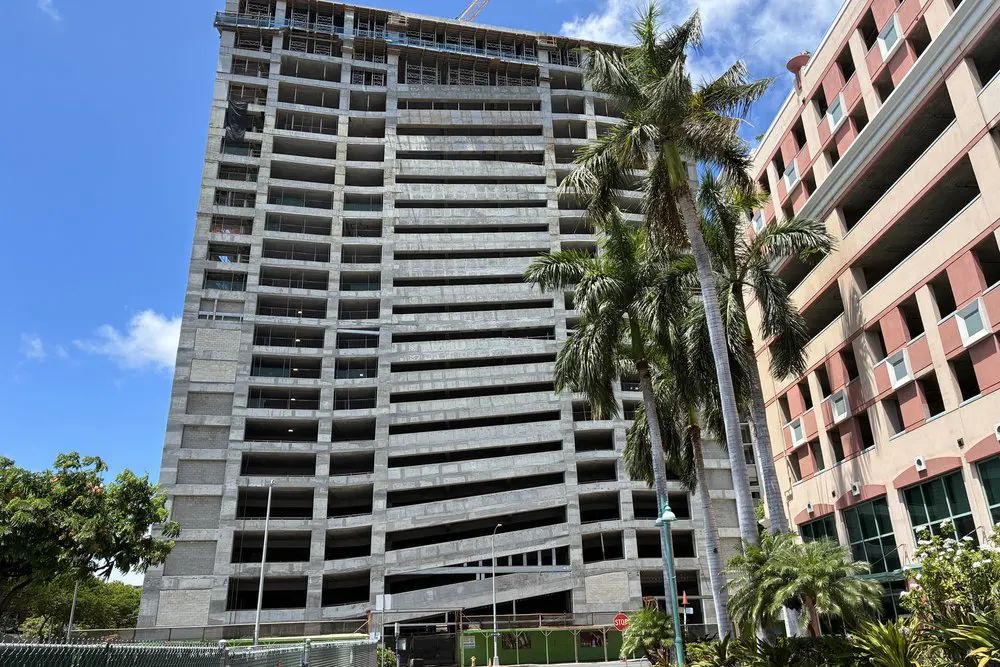 Front street-level view of the parking building framed by palm trees.