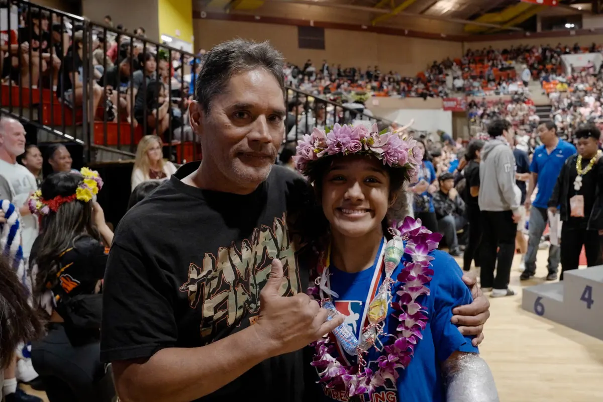 Father celebrating his daughter's success in a wrestling tournament.