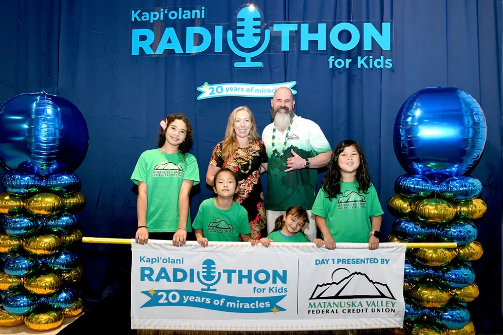 Donors and children holding radiothon banner.