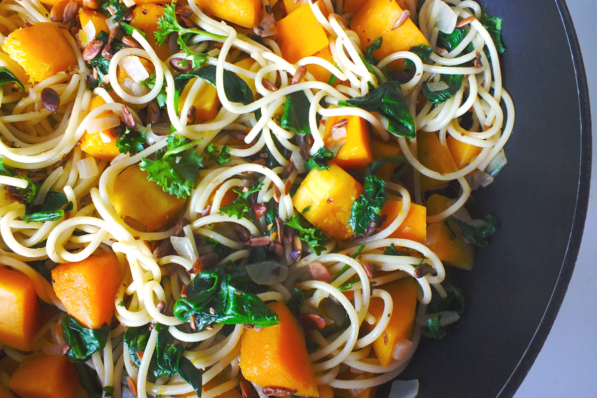 Pasta with butternut squash and greens on a plate.
