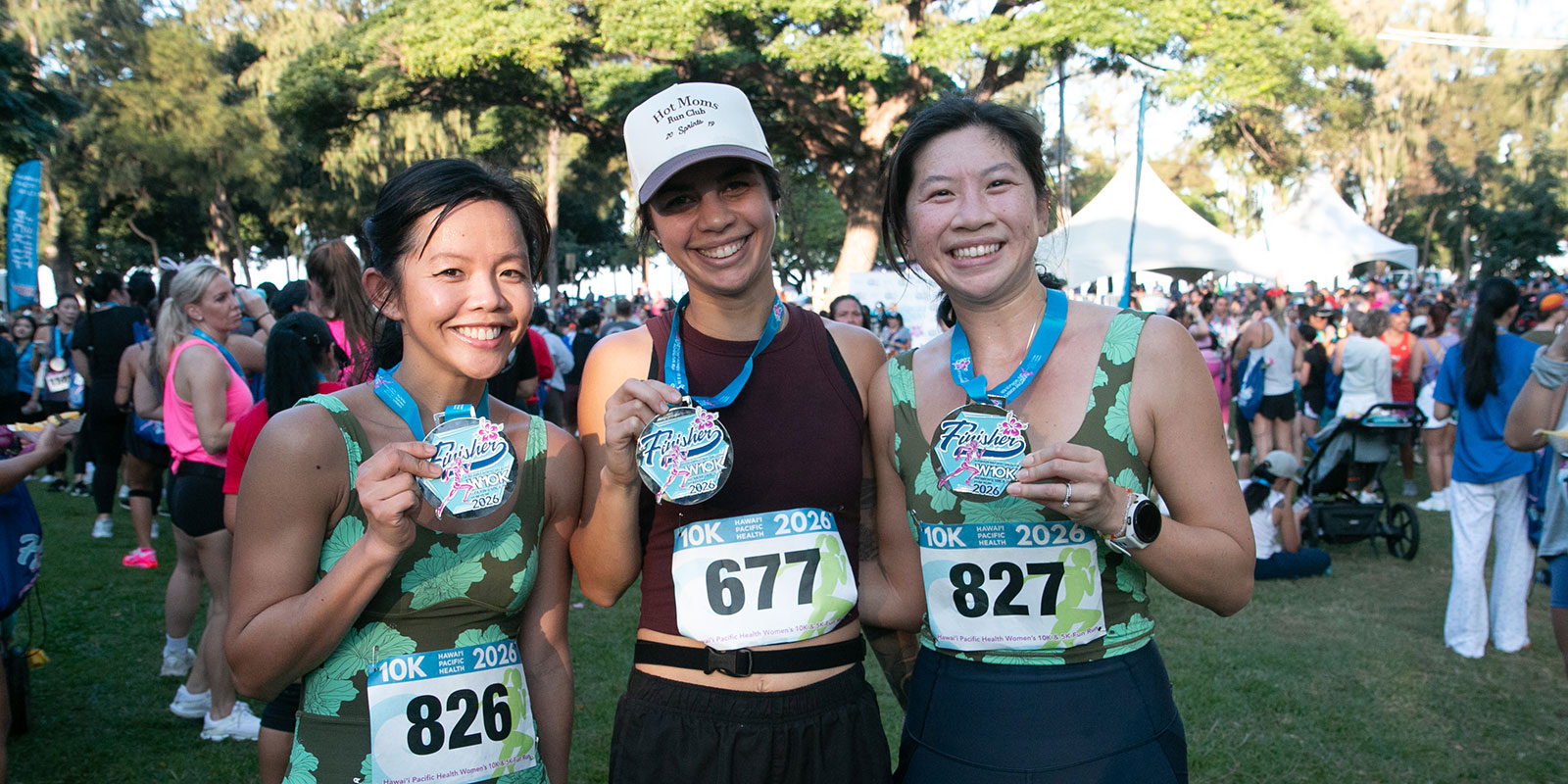 A team of three smiling runners holding finisher medals.