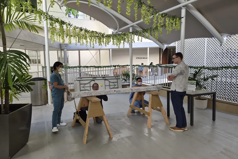 Two team members hold the signed construction beam across wooden supports.