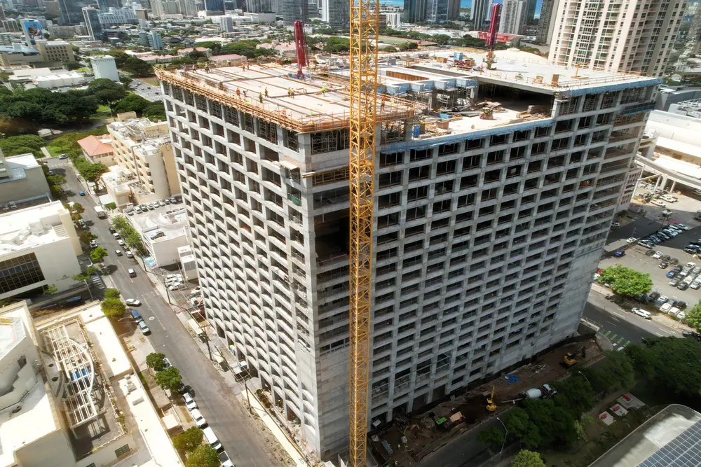 Aerial corner view showing rooftop construction and the tower crane.