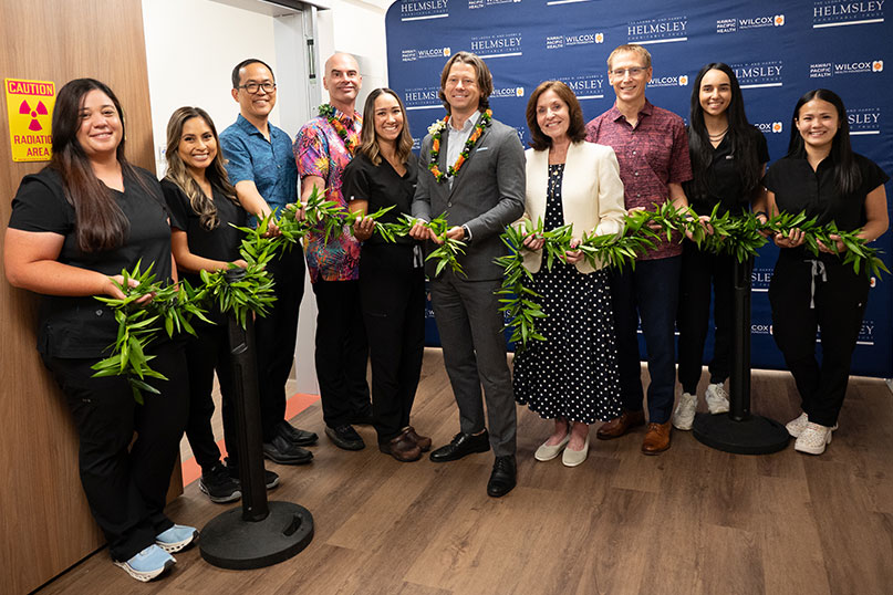 Group shot of healthcare providers, executives and donors holding a long maile lei as part of the interventional radiology suite blessing.