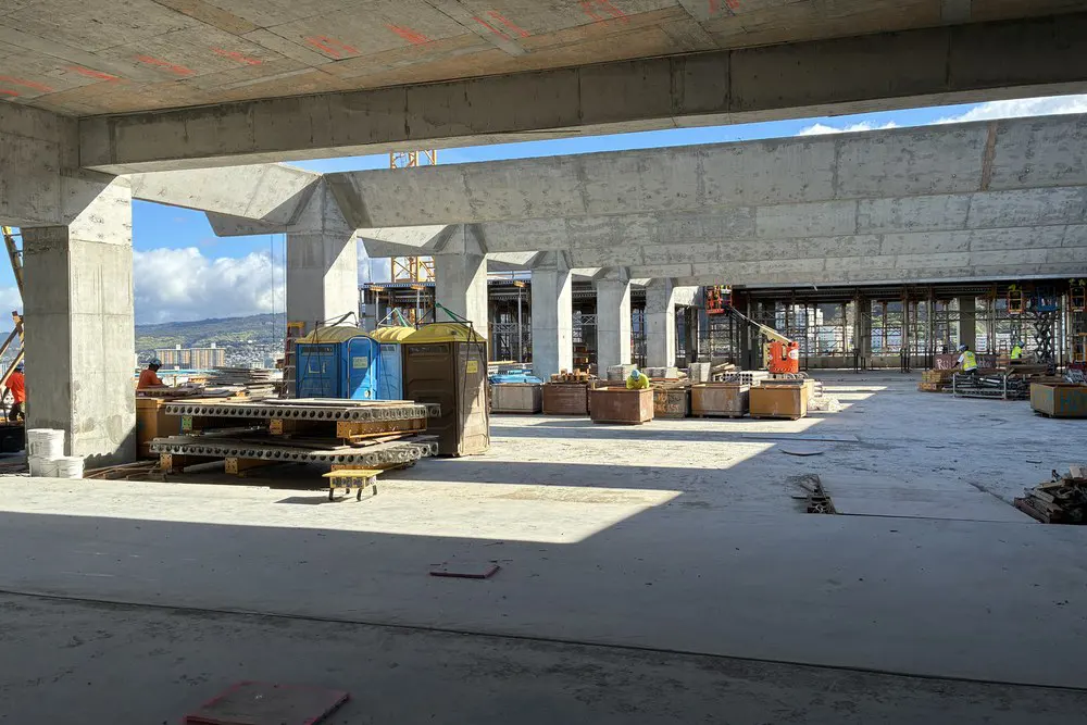 Concrete trellis beams frame equipment and materials across the rooftop work zone.