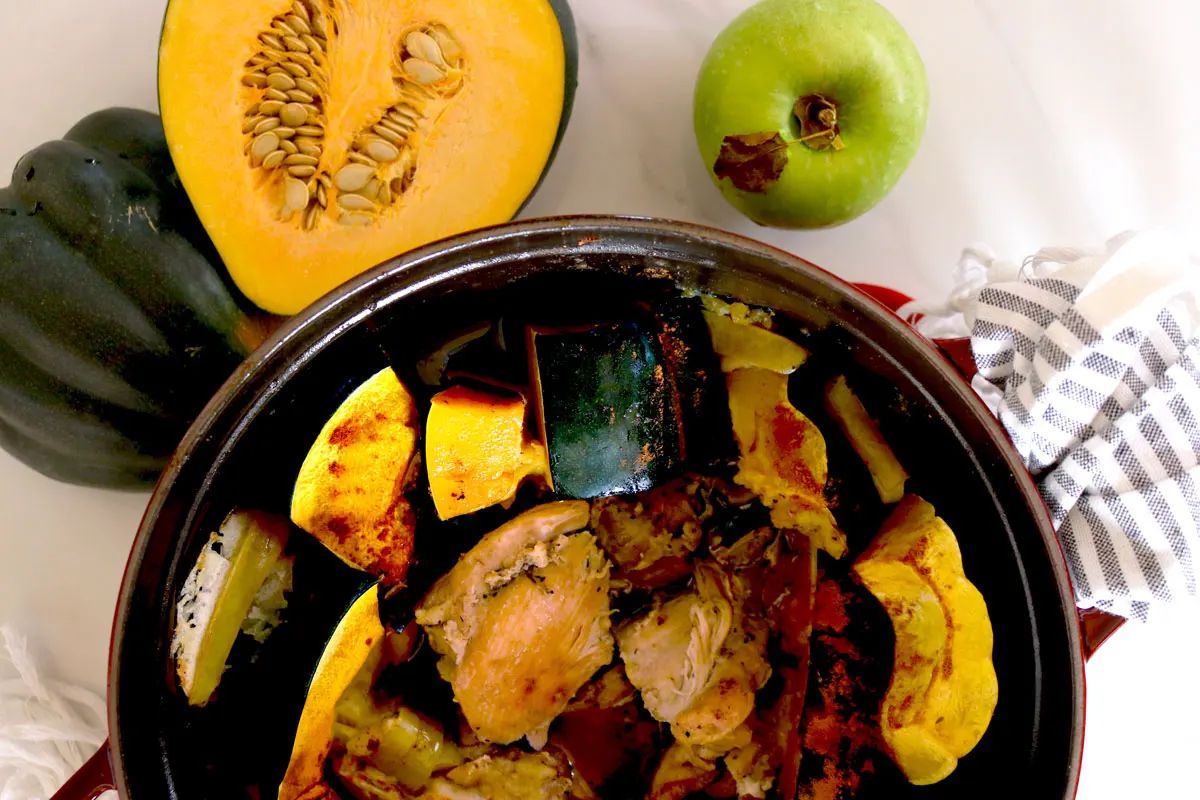 Acorn squash and chicken pieces sit in a large pot