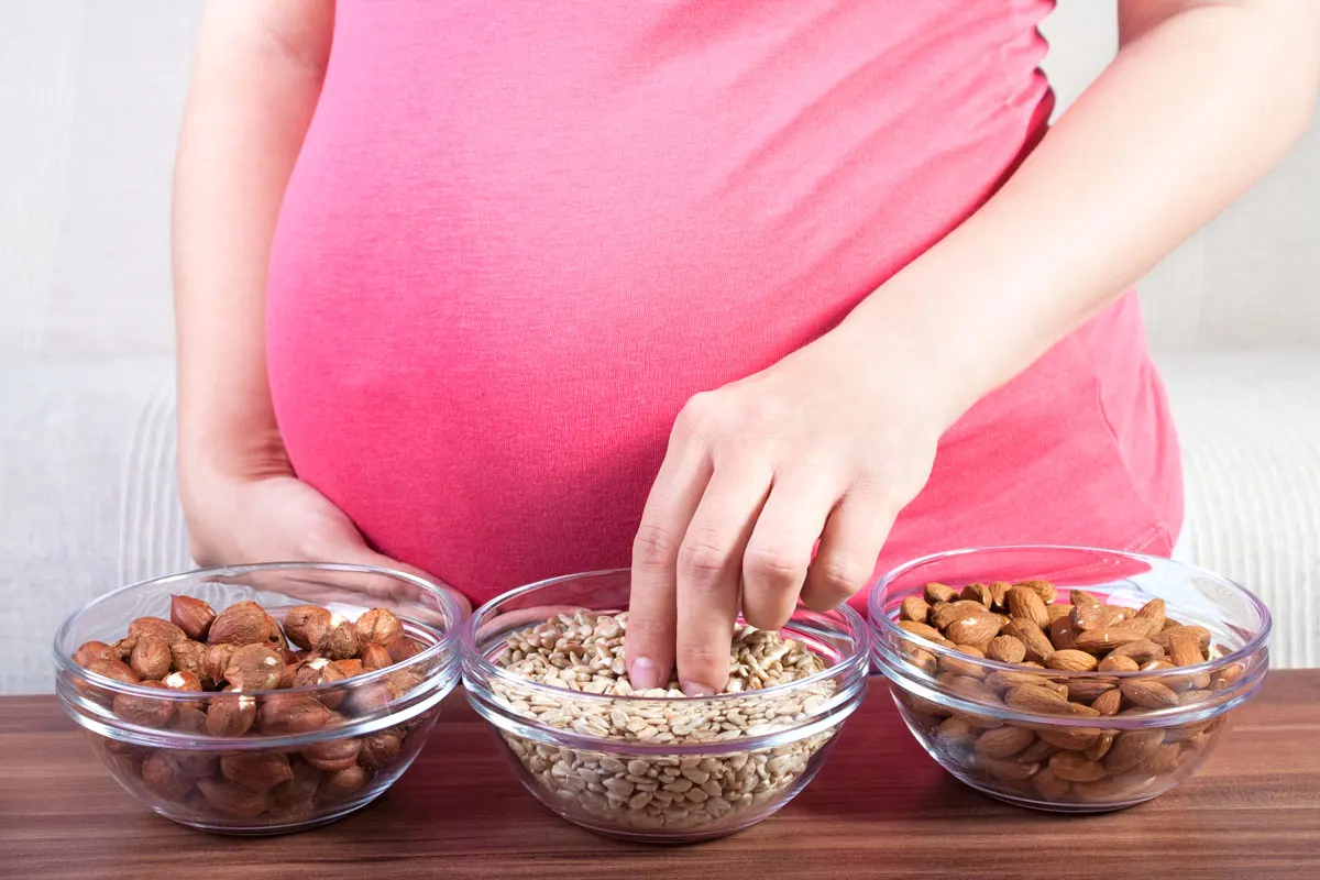 Pregnant woman eating various nuts.
