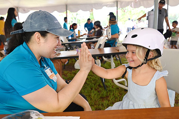 Pediatrician high fiving a young girl wearing a new bike helmet.