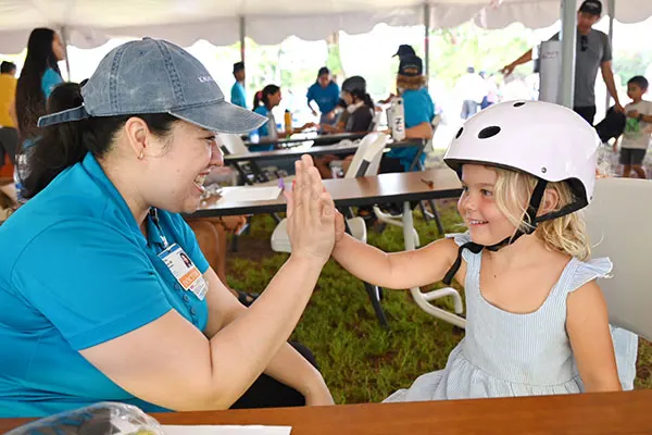 Pediatrician high fiving a young girl wearing a new bike helmet.