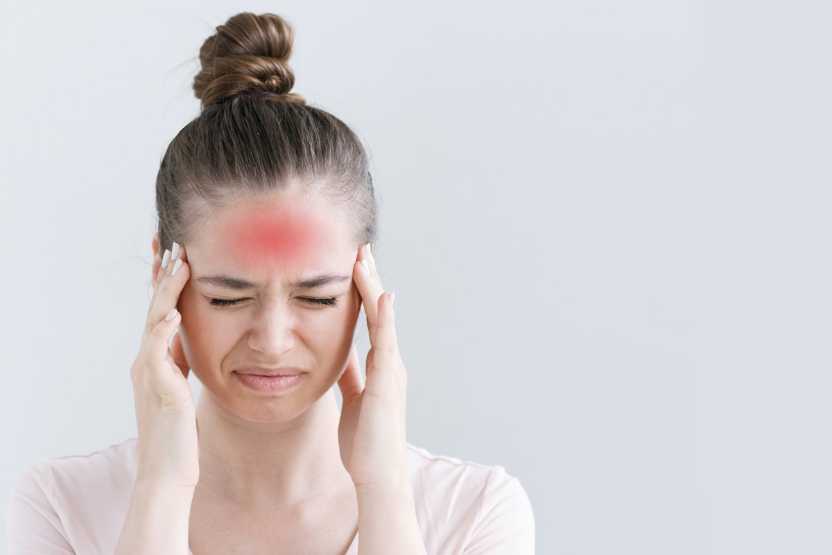 Woman with a headache holds her head in pain.
