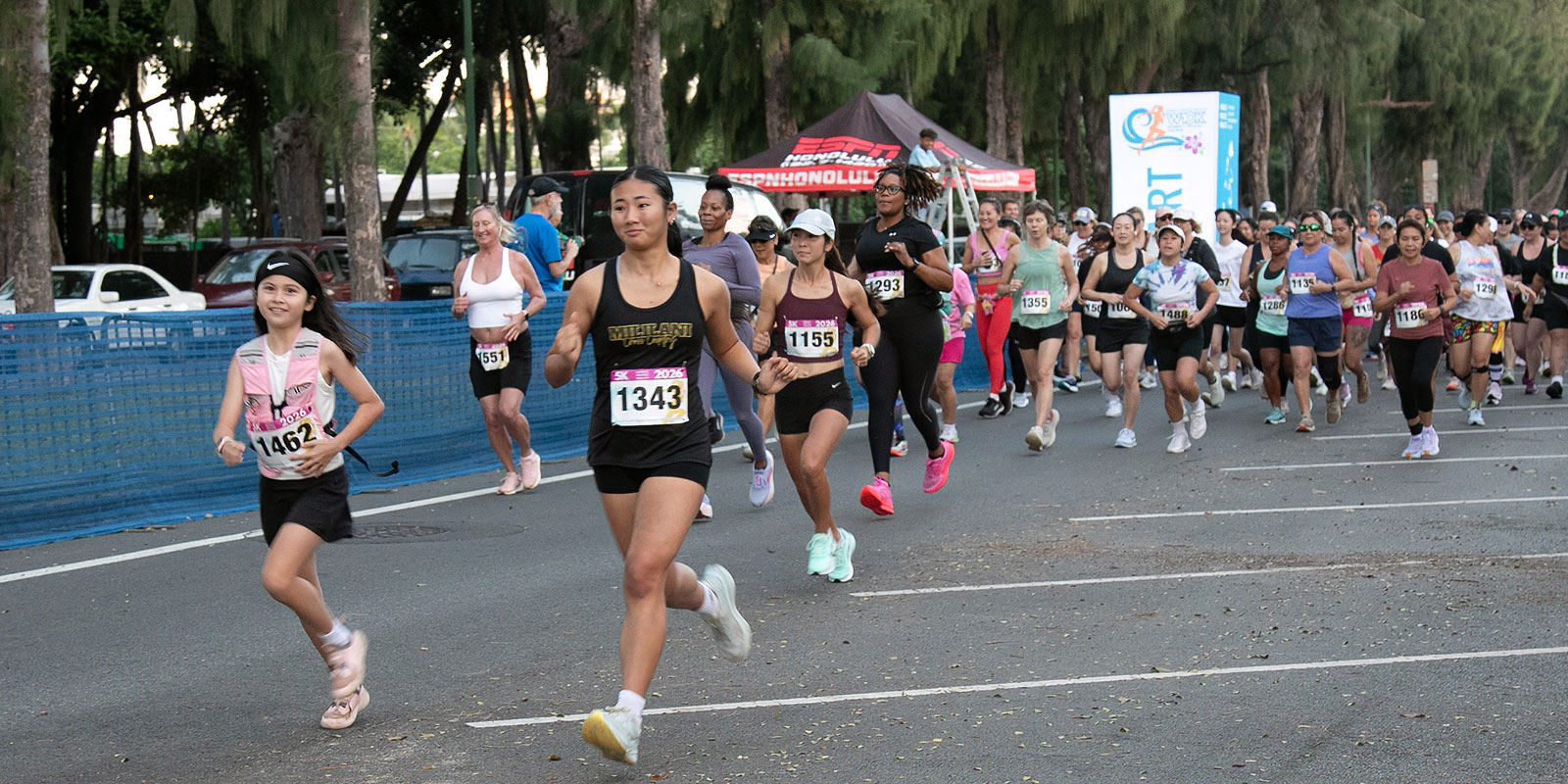 Large group of female runners of all ages taking off from the race starting line.